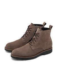 Botas de tobillo de ante marrón con puntera redondeada, cordones en la parte delantera, costuras en contraste y lengüetas en el talón. Suela de goma flexible.