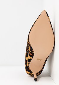 Lodičkový podpatek s leopardím vzorem a špičatou špičkou, černý a žlutý texturovaný materiál a hladká nahá podrážka. Viditelný detail bočního zipu.