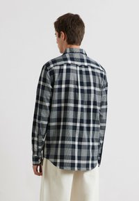 Langärmliges Hemd in navy und grau mit kariertem Muster, Knopfmanschetten und einer Rückenpasse. Weicher Stoff mit lockerer Passform und abgerundetem Saum.