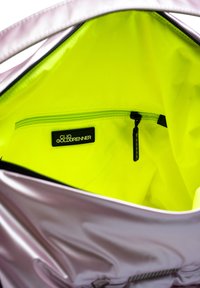 Interieur van een roze, glanzende handtas met een felgele voering en een zwarte ritssluiting met een label met de tekst "Clio Goldbrener."