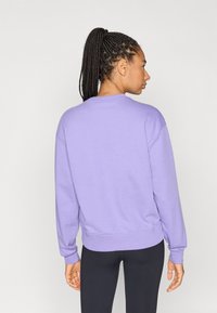 Μπλούζα φούτερ λεβάντας με μακριά μανίκια, στρογγυλή λαιμόκοψη και ριμπ μανσέτες. Μαλακή υφή και άνετη εφαρμογή, σε συνδυασμό με μαύρο κολάν.