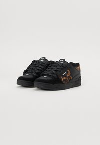 Black sneakers with a suede and leather upper, featuring a tie-dye pattern on the side, textured laces, and a rubber sole.