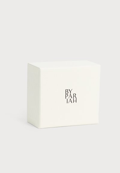 Boîte rectangulaire blanche texturée avec texte noir "BY PARIAH" centré sur le devant sur un fond clair uni.