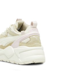 Beżowo-kremowe trampki z teksturowaną siateczkową cholewką, zamszowymi akcentami i masywną białą podeszwą. Zawierają różową pętelkę na pięcie oraz logo RS-X.