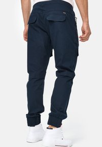 Pantalones cargo azul marino con cinturilla elástica, dos bolsillos traseros y puños ajustados. Hechos de una tela ligera con una textura suave.