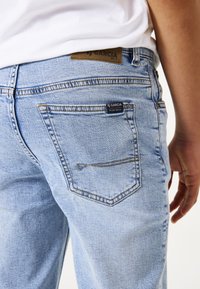 Hellblaue Denim-Jeans mit klassischem Fünf-Taschen-Design, einem Leder-Patch von Garcia am Bund und sichtbaren Nähdetails.