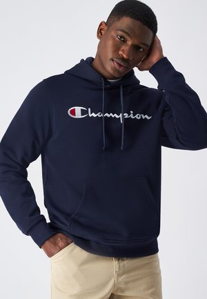 Navy-blaues Kapuzenpullover aus weichem Stoff mit einer Fronttasche, Kordeln und einem auffälligen gestickten 'Champion'-Logo in Weiß und Rot.