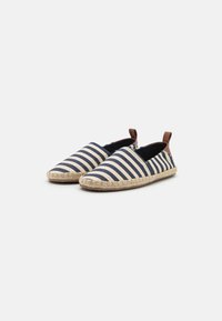 Striped espadrille slip-ons in navy and beige, featuring a textured fabric upper, woven jute sole, and leather accent at the heel.