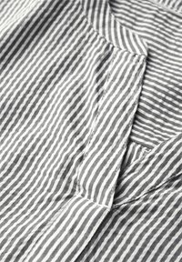 Gray and white striped fabric with a soft texture, featuring a collar and stitching details along the placket and hem.