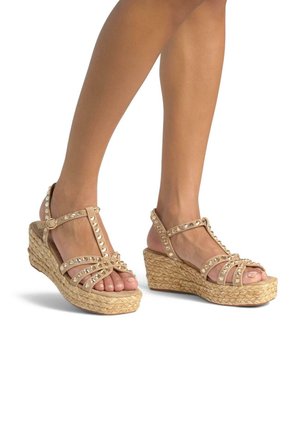 Beige wedge sandals with braided jute sole, featuring multiple crisscross straps adorned with clear rhinestones. Adjustable ankle strap included.