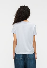 Ανοιχτό γαλάζιο T-shirt με κοντά μανίκια και στρογγυλή λαιμόκοψη, κατασκευασμένο από βαμβάκι. Η πίσω πλευρά είναι απλή, με διακριτικές ραφές.