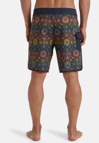 Shorts de bain colorés avec un motif géométrique en orange, vert et bleu. Comprend une poche latérale et une taille noire.