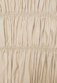 Tissu beige froncé à la texture lisse, présentant des rangées horizontales de fronces élastiques pour plus d'élasticité et de profondeur.