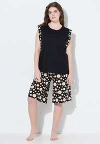 Zwarte mouwloze top met stippen op de schouder, gecombineerd met zwarte shorts met grote beige stippen. Lichtgewicht stof, casual ontwerp.