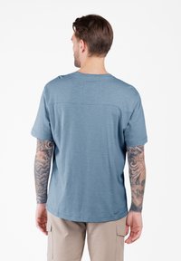 Camiseta azul de manga corta con cuello redondo, que presenta una textura suave y una costura horizontal en la parte superior de la espalda.