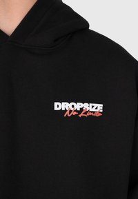 Sweat à capuche noir avec du texte blanc et rouge sur la poitrine lisant "DROPSIZE No Limits" sur le côté gauche.