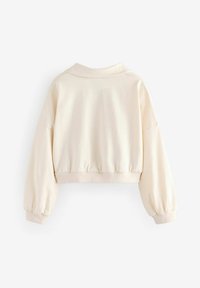 Cremefarvet cropped sweatshirt med polo-krave og pyntede manchetter. Blød tekstur med en afslappet pasform og minimalistisk design.