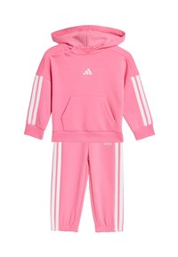 Sudadera con capucha rosa y pantalones a juego de tela suave, con acentos de tres rayas blancas y un bolsillo frontal tipo canguro.