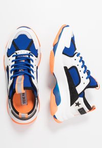 Scarpe da ginnastica atletiche blu con accenti bianchi e neri. Tomaia in mesh, suola testurizzata, dettagli arancioni e logo nero sul retro.