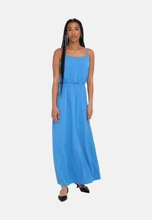 Robe maxi bleue avec des bretelles fines, taille froncée et une silhouette fluide. Portée avec des talons aiguilles noirs. Tissu lisse avec un éclat subtil.