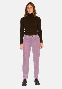 Pantalons en velours côtelé violet avec une coupe droite et une texture à côtes verticales ; associés à un col roulé noir à côtes et des chaussures noires.