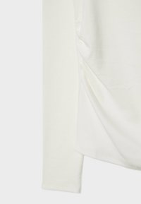 Long-sleeve white top made of soft fabric, featuring a gathered detail on one side and a smooth texture. Simple design with a round neckline.