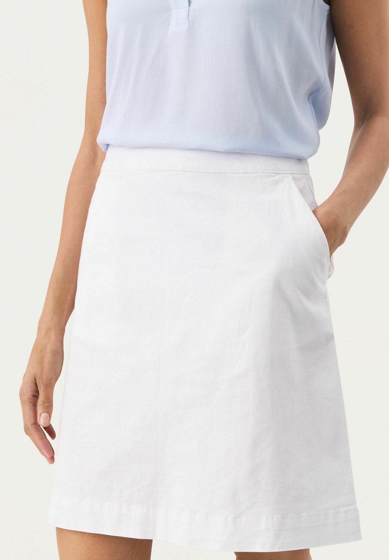 Jupe en coton blanc avec une taille ajustée et des poches latérales. Présente une silhouette droite et un ourlet qui tombe juste au-dessus du genou.