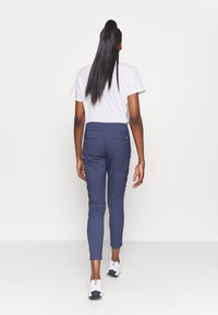 Námořnické modré sportovní kalhoty se slim fit střihem, elastickým pasem a dvěma zadními kapsami. Spárováno s jednoduchým bílým tričkem a bílými teniskami.