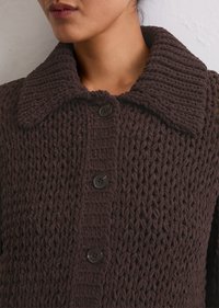 Cardigan lavorato a maglia marrone scuro con un ampio colletto e cinque bottoni neri. Tessuto strutturato con un motivo a punto spesso.