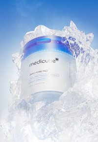 Medicube Zero Pore Pad i en genomskinlig behållare med blått lock, som visar en slät yta och etiketter med ingredienser och vikt.