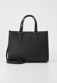 Sac à main en cuir noir avec une finition texturée, deux poignées supérieures, une bandoulière réglable et des accessoires en métal argenté. Logo Lacoste centré.