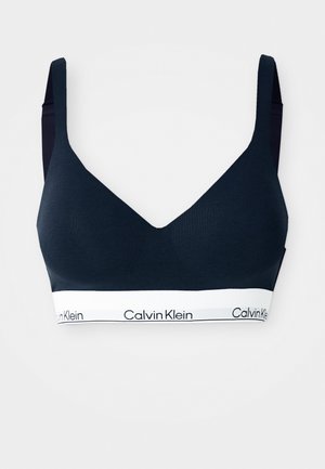 Bralette bleu marine à décolleté V profond, en tissu doux, avec des bretelles larges et une bande élastique blanche ornée du logo "Calvin Klein".