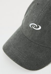 Mørkegrå bomuldsbaseballcap med en buet skygge og et sølvlogo på forsiden. Tekstureret stof med fine lodrette striber.