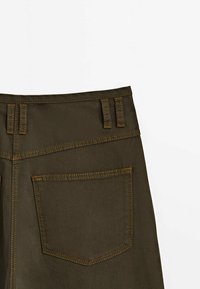 Shorts en denim vert olive avec des coutures contrastées, une poche arrière et des passants de ceinture à la taille. Texture lisse, design structuré.