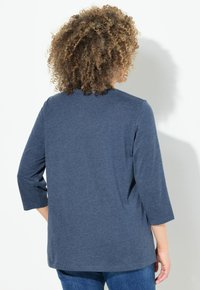 Dunkelbluse Langarmshirt mit Rundhalsausschnitt und 3/4-Ärmeln. Weicher Stoff, lässige Passform, und die Rückansicht hebt das schlichte Design hervor.