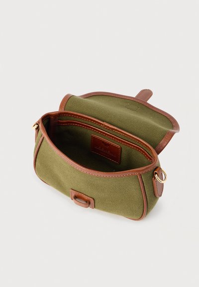 Τσάντα χιαστί από ύφασμα ελιάς με καφέ δερμάτινη επένδυση, άνοιγμα με καπάκι και χρυσό μεταλλικό δαχτυλίδι στο πλάι, εμφανιζόμενη ανοιχτή σε λευκό φόντο.