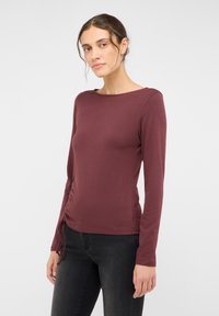 Langarmshirt in Burgunderrot mit Rundhalsausschnitt und Raffung an der Seite, hergestellt aus weichem, elastischem Baumwollstoff.