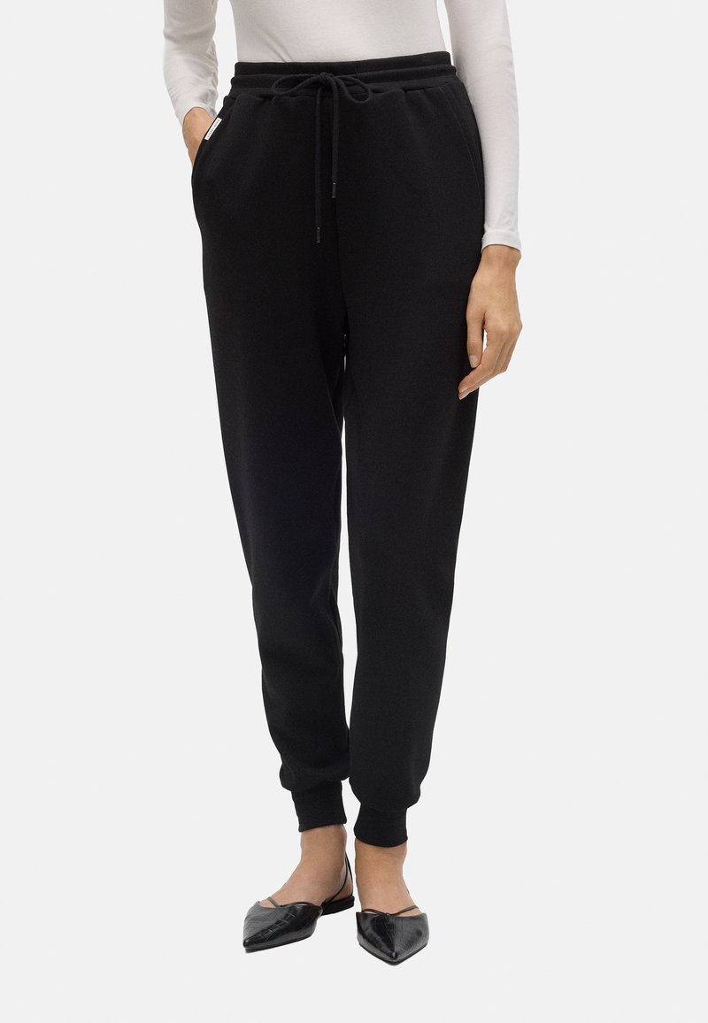 Pantalones deportivos negros hechos de un tejido suave, con una cintura elástica con cordón, bolsillos laterales y tobillos ajustados.