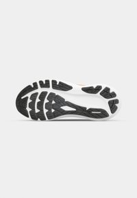 Athletic shoe outsole with a black rubber tread pattern, featuring white midsole and orange accents. Textured for grip and traction.