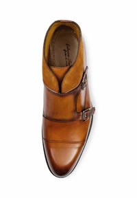 Bottines en cuir tan avec des accents en suède, double boucle, bout rond et couture texturée. Fini lisse avec un aspect brillant.