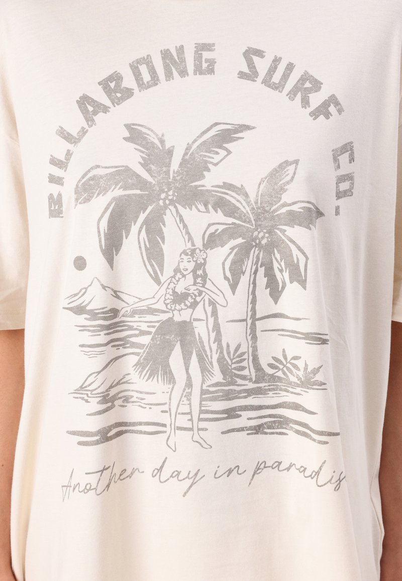 T-shirt de surf Billabong en crème avec un graphisme argenté représentant une danseuse hula entourée de palmiers et le texte "Un autre jour au paradis."