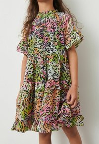 Pestrobarevné šaty s volánkovým lemem. Vyznačují se zvířecím potiskem v růžové, zelené, oranžové a černé barvě na lehké tkanině. Elastický výstřih a rukávy.