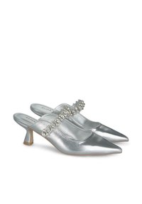Scarpe con tacco slingback in metallo argento con punte appuntite, caratterizzate da un cinturino decorato con cristalli e un tacco basso a blocco. Texture liscia in tutto il prodotto.
