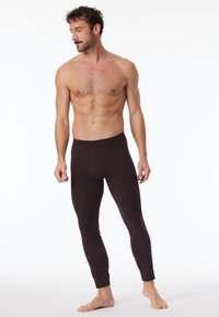 Braune thermische Leggings aus einem weichen Stoff, mit einer engen Passform, elastischem Bund und schmal zulaufenden Beinen. Keine auffälligen Muster oder Akzente.