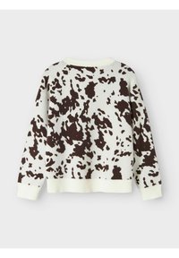 Maglione lavorato a maglia di colore crema con motivo a macchie di mucca marroni. Presenta polsini e orlo a costine, spalle ribassate e una vestibilità ampia. Tessuto morbido.