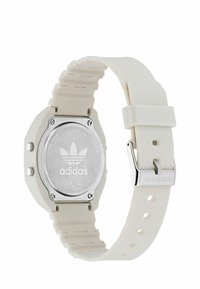 Balta silikono juosta su sidabriniu nerūdijančio plieno dangteliu. Yra oktagoninė dėklo forma ir aiškiai matoma Adidas logo.