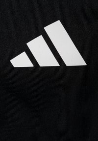 Tissu noir affichant un logo à trois rayures blanches, comportant trois parallélogrammes de taille progressivement plus grande disposés en diagonale, texture lisse.