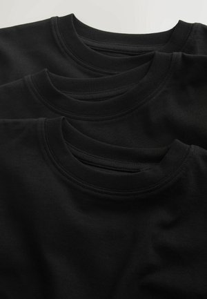 Trois t-shirts en coton noir empilés, présentant des encolures rondes avec bords côtelés. Texture douce et finition lisse, sans logos ni motifs visibles.