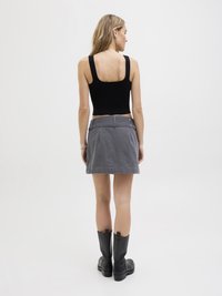 Fekete bordázott cropped tank top szürke farmer mini szoknyával és fekete térd fölé érő csizmával párosítva. Egyszerű dizájn, egyenes vonalakkal és minimális részletekkel.