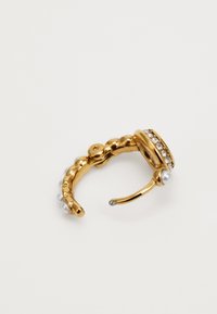 Bague bracelet dorée avec un bandeau texturé, ornée de petites perles et d'une rangée de pierres claires serties sur le dessus. Fini lisse et brillant.